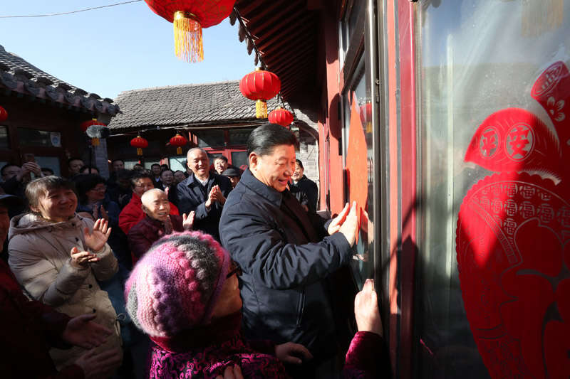 2019年2月1日上午，習(xí)近平在北京前門東區(qū)草廠四條胡同32號(hào)院，高興地拿起一幅“?！弊?，親自貼到門上，給這里的老街坊們拜年。新華社記者 鞠鵬 攝